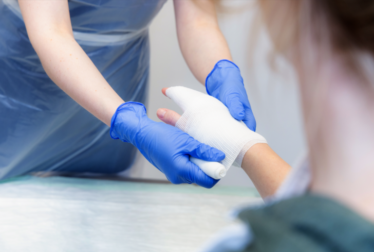 Person verbindet Hand mit einer Mullbinde